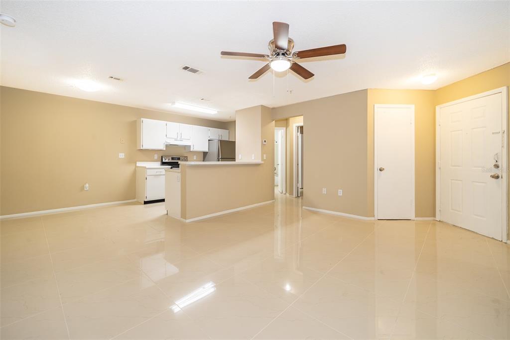 An open-concept living area features light-colored tile floors, a kitchen with white cabinets, and a ceiling fan — 623 DORY LANE UNIT 204, ALTAMONTE SPRINGS, FL