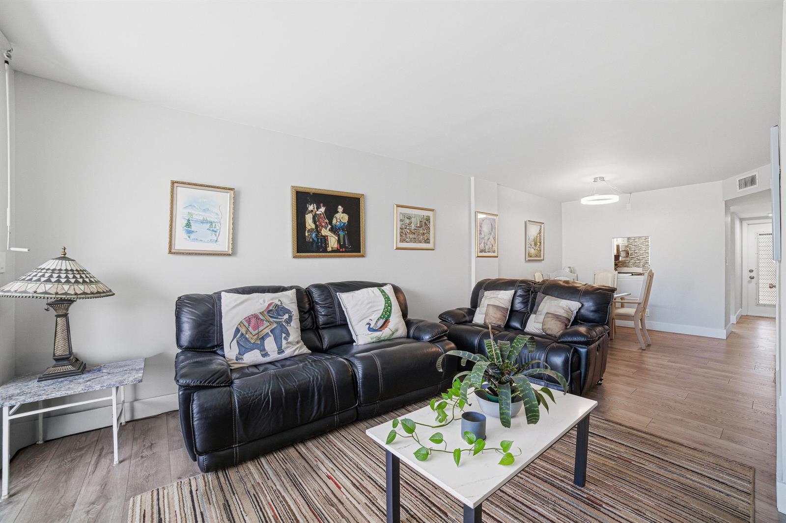 A living room features two black leather sofas, a coffee table, and framed wall art — 367 S Federal Highway # C323, Deerfield Beach FL 33441, DEERFIELD BEACH, FL