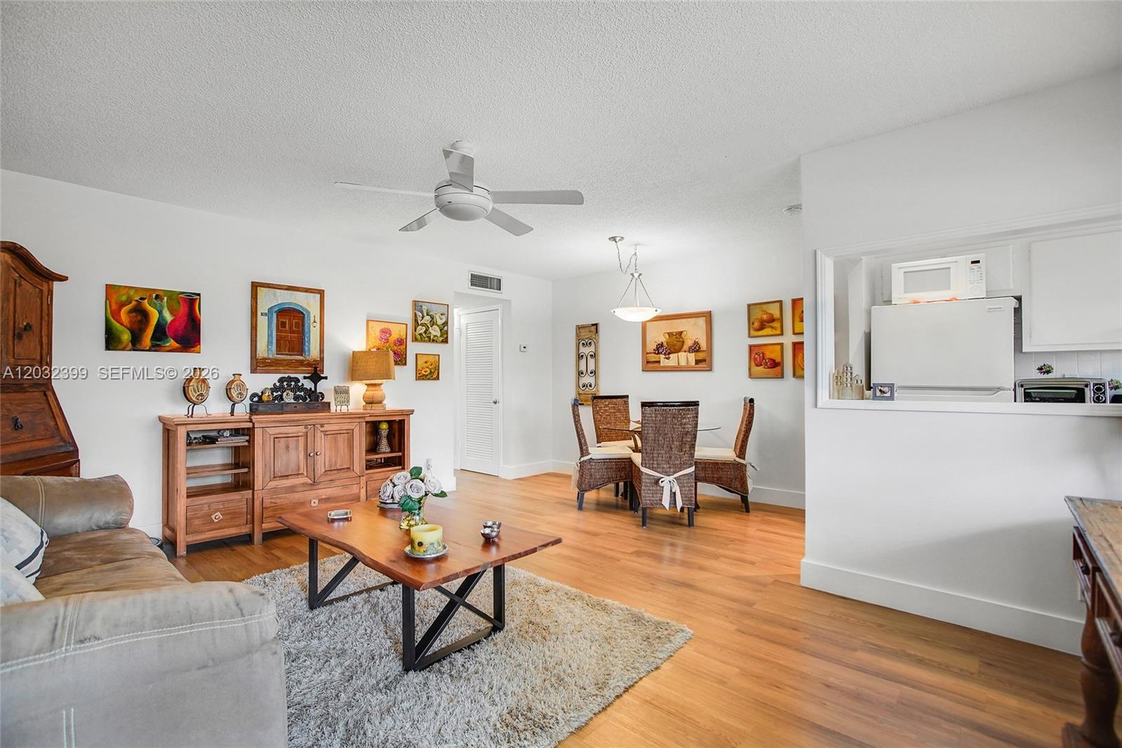 A living and dining area features wood flooring, a ceiling fan, and a pass-through kitchen — 5300 Washington St # O224, Hollywood FL 33021, HOLLYWOOD, FL