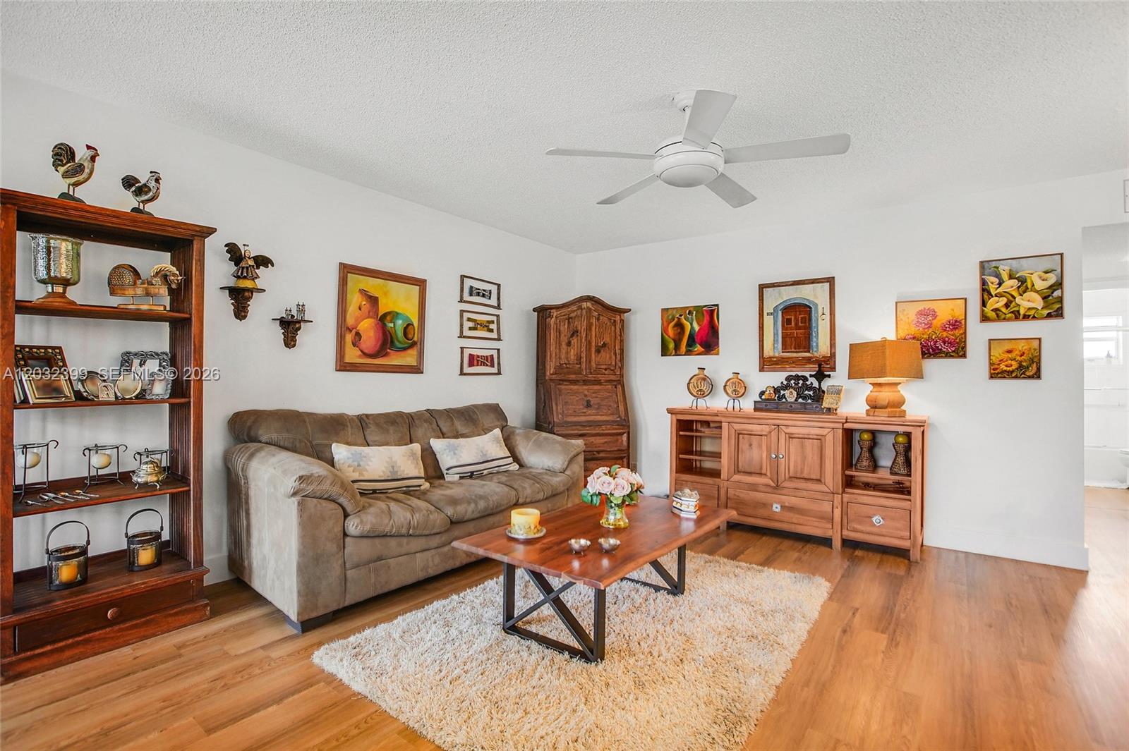 A living room features a brown sofa, wooden furniture, a coffee table, and wall art — 5300 Washington St # O224, Hollywood FL 33021, HOLLYWOOD, FL