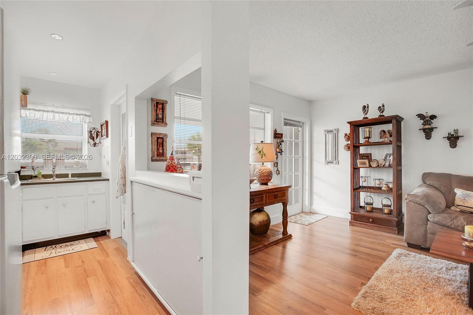 A kitchen with white cabinets opens into a living area with wood-look flooring — 5300 Washington St # O224, Hollywood FL 33021, HOLLYWOOD, FL