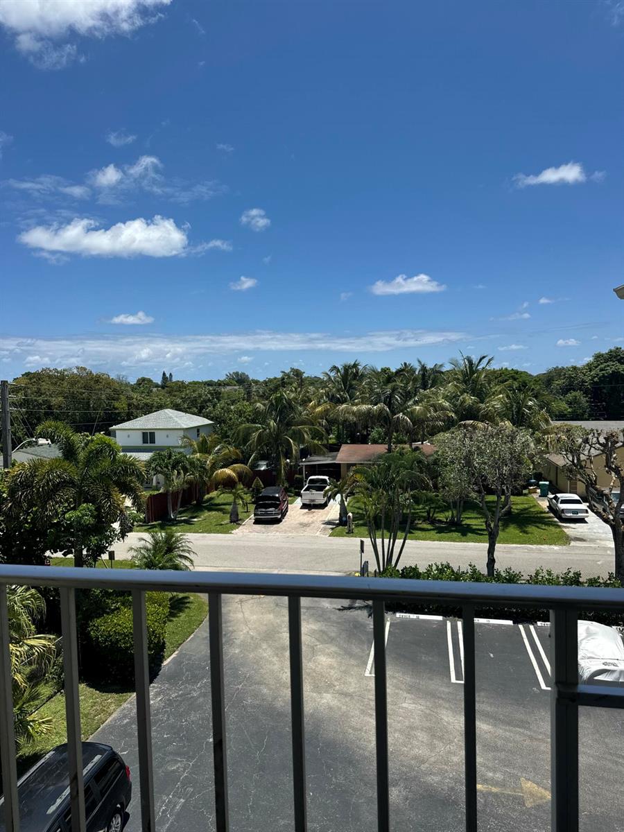 A view from a balcony overlooking a parking lot, a street, and residential houses with trees — 2615 NE 3rd Court # 4120, Boynton Beach FL 33435, BOYNTON BEACH, FL