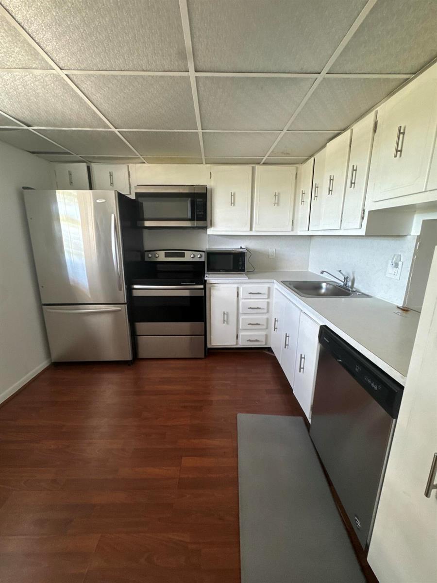 A kitchen featuring white cabinets, stainless steel appliances, a drop ceiling, and wood-look flooring — 2615 NE 3rd Court # 4120, Boynton Beach FL 33435, BOYNTON BEACH, FL