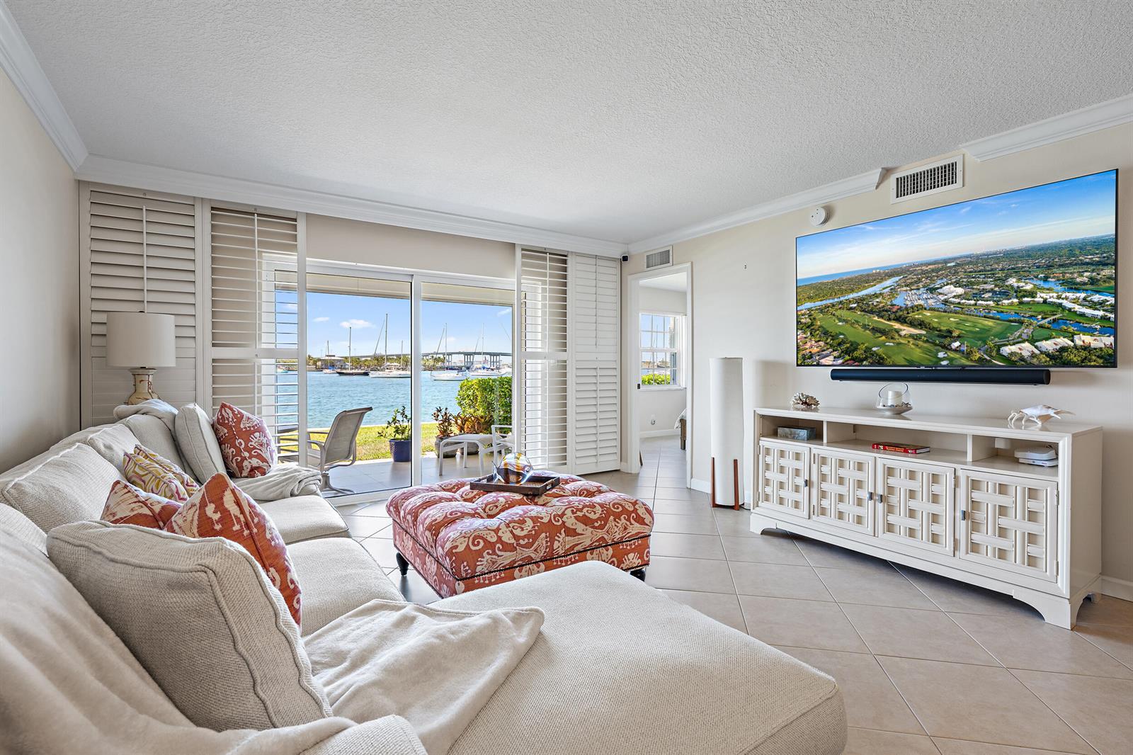 A living room features a sectional sofa, patterned ottoman, and sliding doors overlooking a marina — 1051 Sugar Sands Boulevard # 156, Singer Island FL 33404, SINGER ISLAND, FL