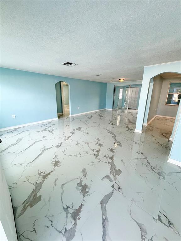 An open living area features light blue walls and high-gloss white marble-patterned tile flooring — 7040 FOX HOLLOW DRIVE, PORT RICHEY, FL