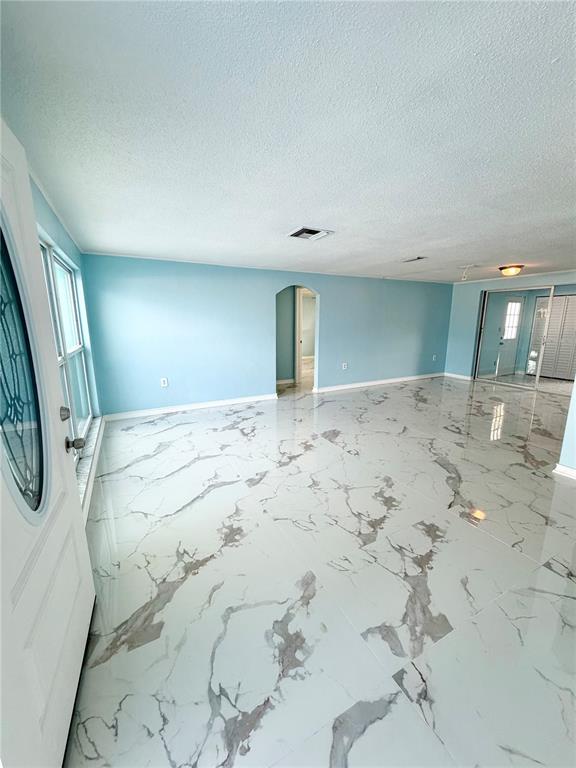 A bright room features light blue walls, white marble-patterned tile flooring, and a glass door — 7040 FOX HOLLOW DRIVE, PORT RICHEY, FL