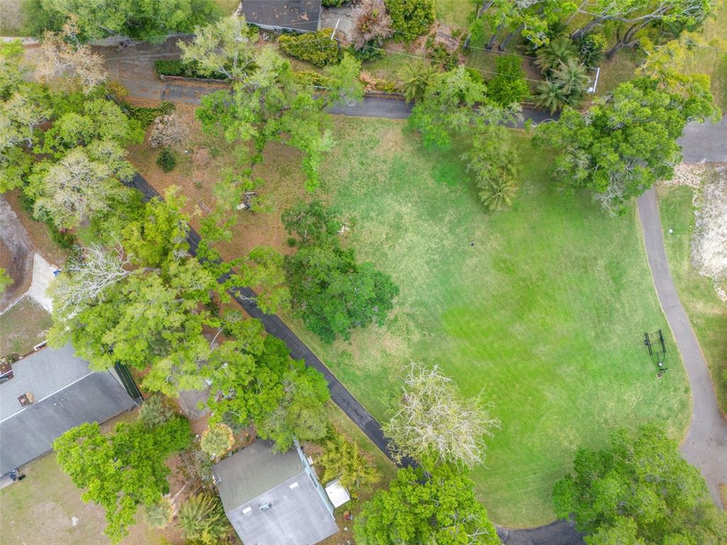An aerial view shows a grassy lot with scattered trees and paved driveways — 5924 RIVER TERRACE, TAMPA, FL