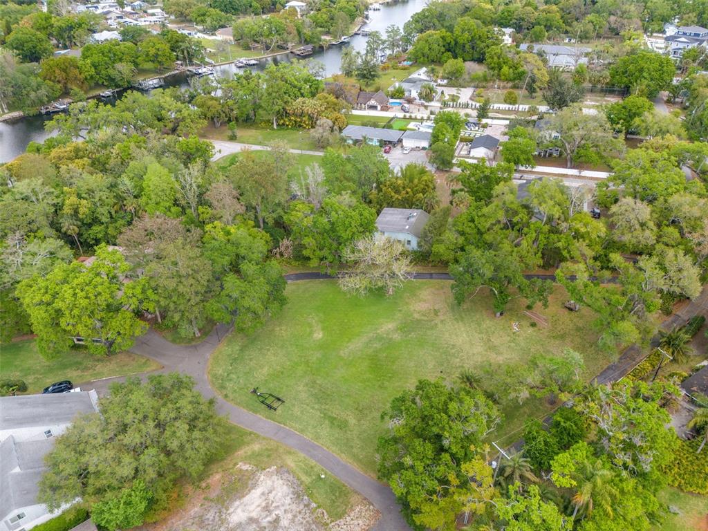 An aerial view shows a large, grassy lot surrounded by mature trees and nearby houses — 5924 RIVER TERRACE, TAMPA, FL