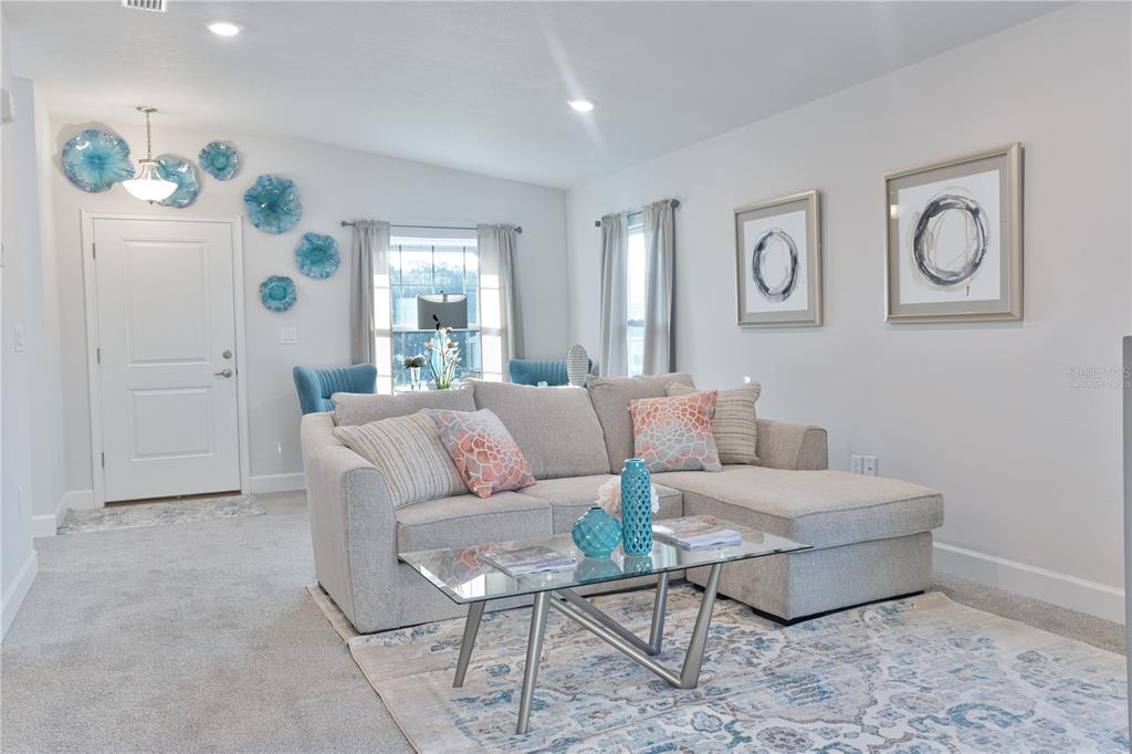 A living room features a gray sectional sofa, a glass coffee table, and blue wall decor — 1841 N ROBERTS TRAIL, BELL, FL