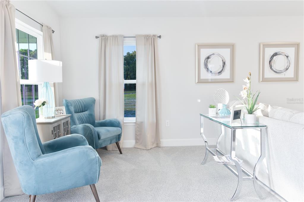 A living room features two blue armchairs, a glass console table, and neutral wall decor — 1841 N ROBERTS TRAIL, BELL, FL