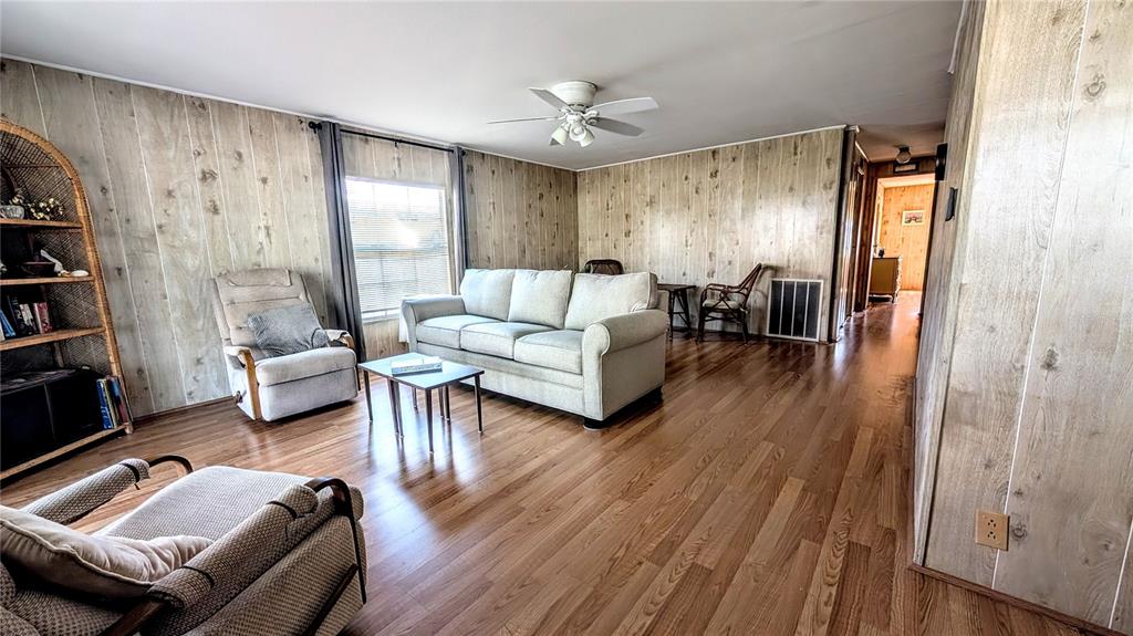A living room features wood-paneled walls, hardwood flooring, a sofa, and two armchairs — 39820 US HIGHWAY 19 N UNIT 199, TARPON SPRINGS, FL