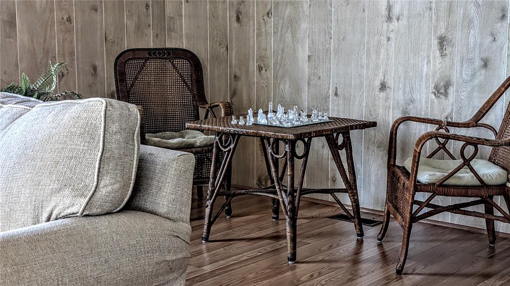 A living room features wood-paneled walls, a wicker table with a glass chess set, and chairs — 39820 US HIGHWAY 19 N UNIT 199, TARPON SPRINGS, FL