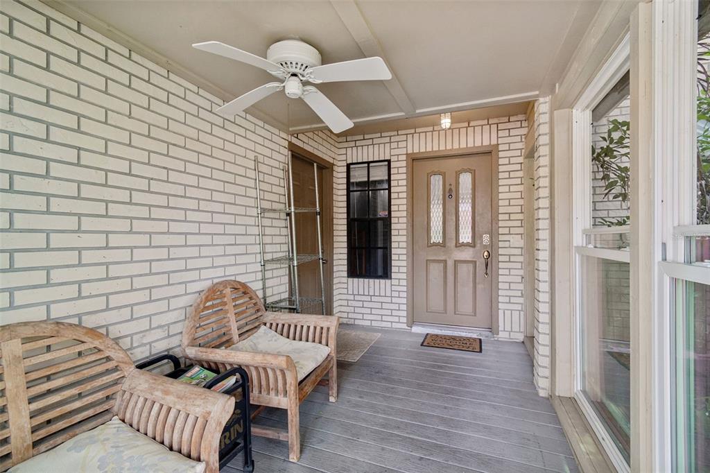 A covered porch features white brick walls, a ceiling fan, and two wooden chairs — 5485 FRIARSWAY DRIVE, TAMPA, FL