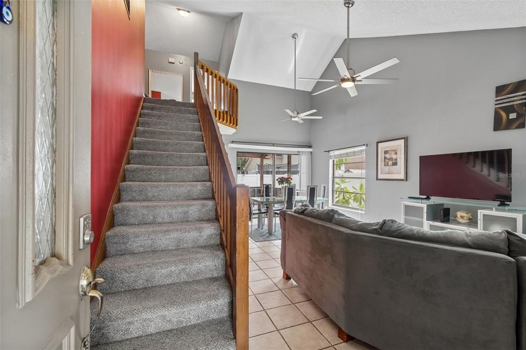 A carpeted staircase leads to an upper level next to a living room and dining area — 5485 FRIARSWAY DRIVE, TAMPA, FL