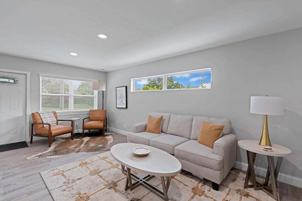 A living room features light gray walls, a beige sofa, two leather chairs, and wood flooring — 2312 Spanish Trail, Delray Beach FL 33483, DELRAY BEACH, FL