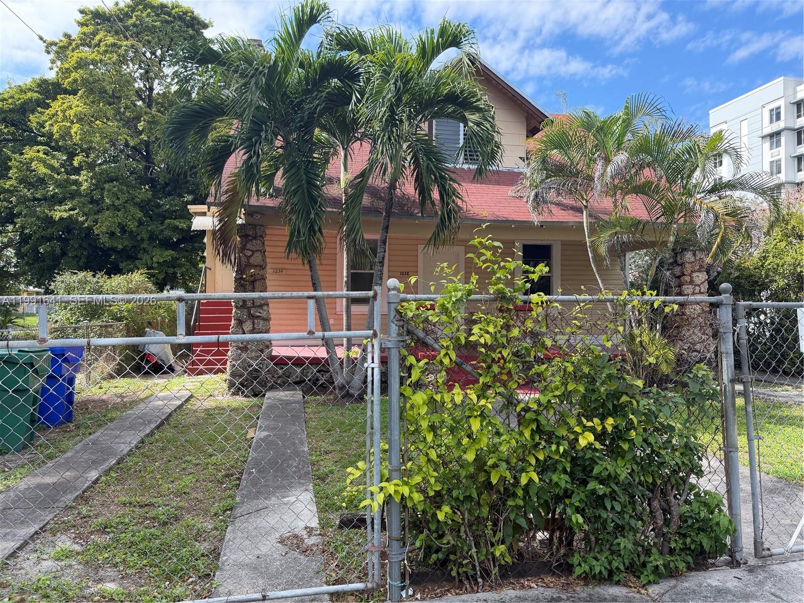 A two-story house with a red roof, stone pillars, and palm trees behind a fence — 1234 NW 9th Ave, Miami FL 33136, MIAMI, FL