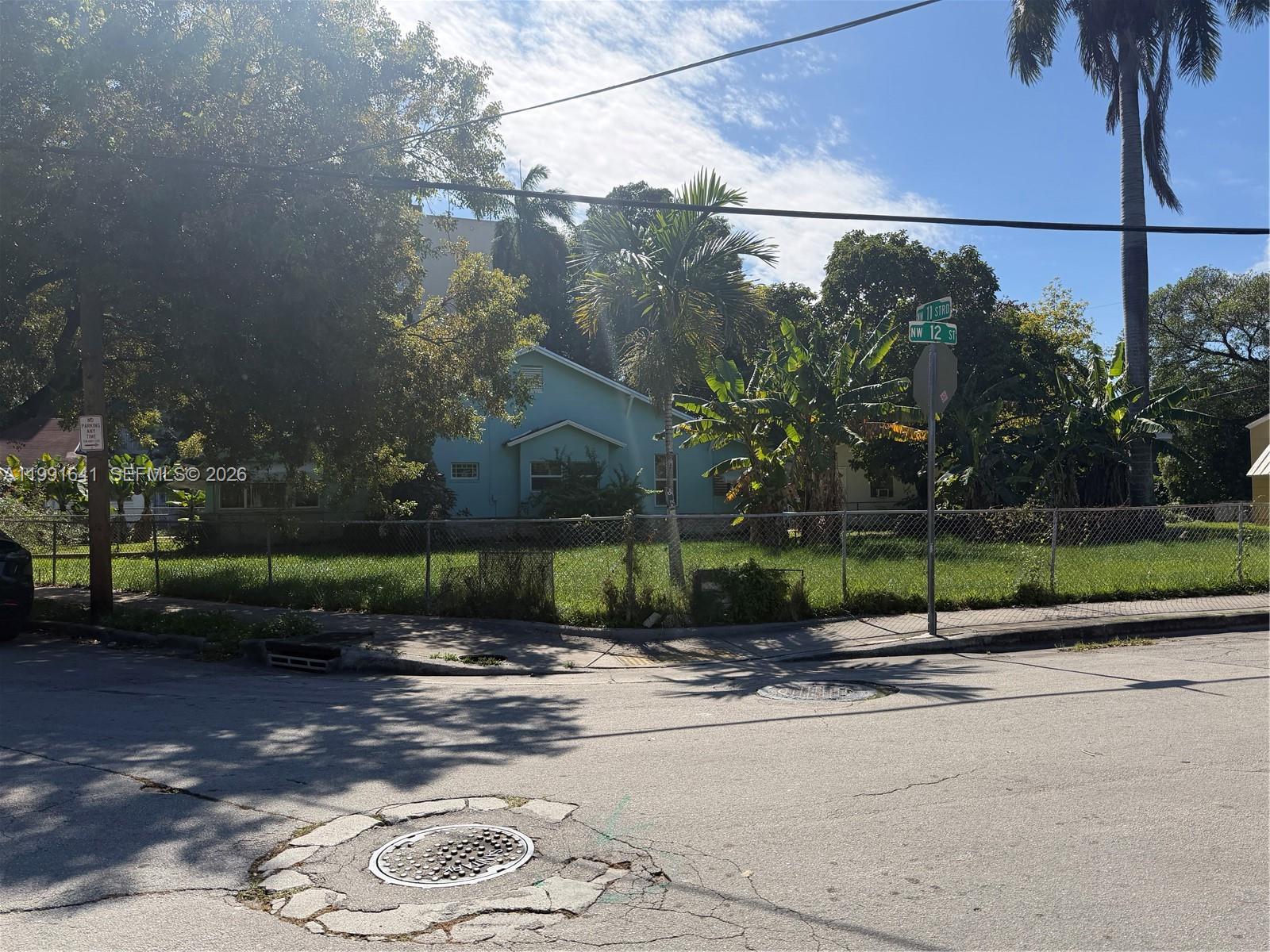 A light blue house sits behind a chain-link fence on a corner lot — 1234 NW 9th Ave, Miami FL 33136, MIAMI, FL