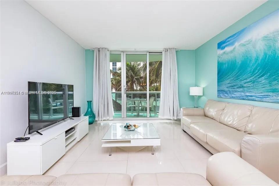 A living room features a white leather sofa, glass coffee table, and a large wave painting — 3901 S Ocean Dr # 2H, Hollywood FL 33019, HOLLYWOOD, FL
