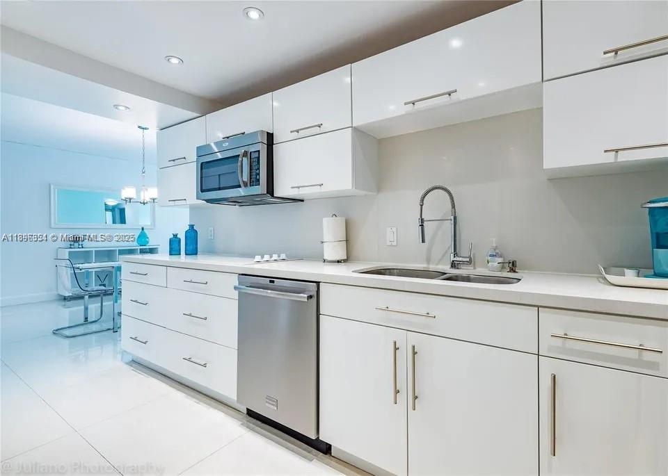 A modern kitchen features white glossy cabinets, stainless steel appliances, and a double-basin sink — 3901 S Ocean Dr # 2H, Hollywood FL 33019, HOLLYWOOD, FL