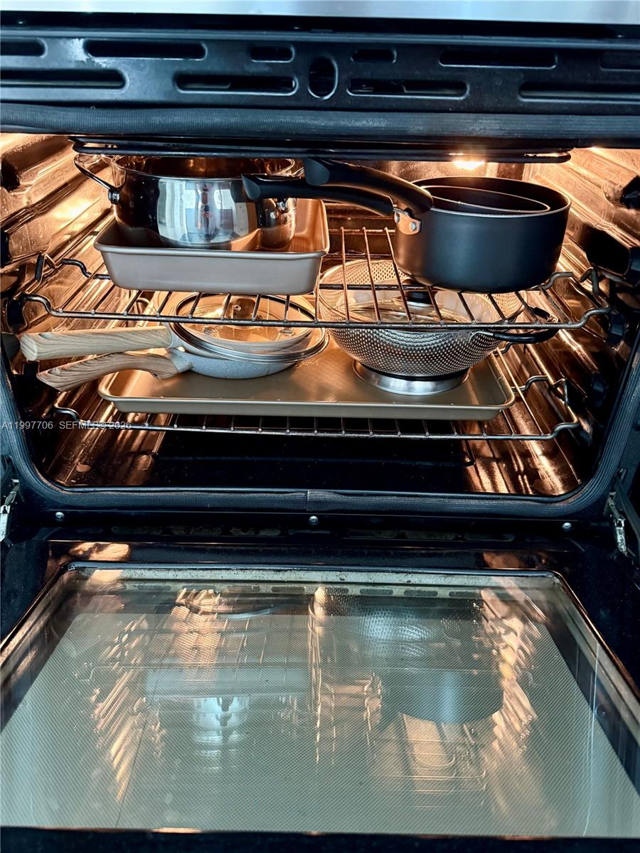 An oven interior is used for storage, containing various pots, pans, and a colander — 50 Biscayne Blvd # 1907, Miami FL 33132, MIAMI, FL