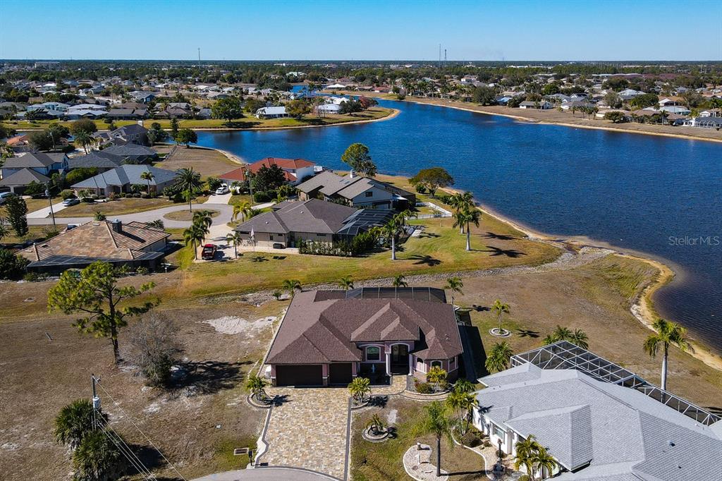 An aerial view shows a residential neighborhood with houses situated along a large lake — 25364 SAINT HELENA LANE, PUNTA GORDA, FL