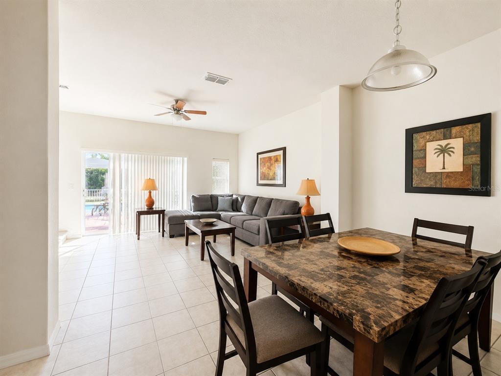 A dining area with a stone-topped table opens into a living room with tile floors — 4558 ADA LANE, KISSIMMEE, FL