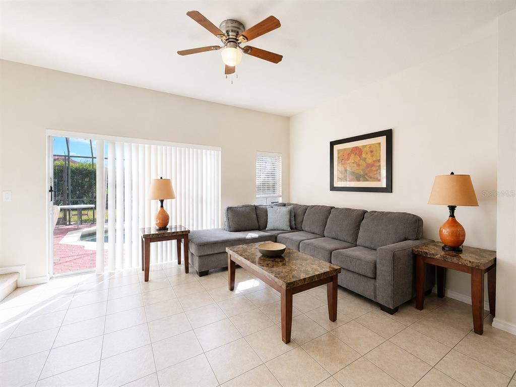 A living room features a gray sectional sofa, a coffee table, and a sliding door — 4558 ADA LANE, KISSIMMEE, FL