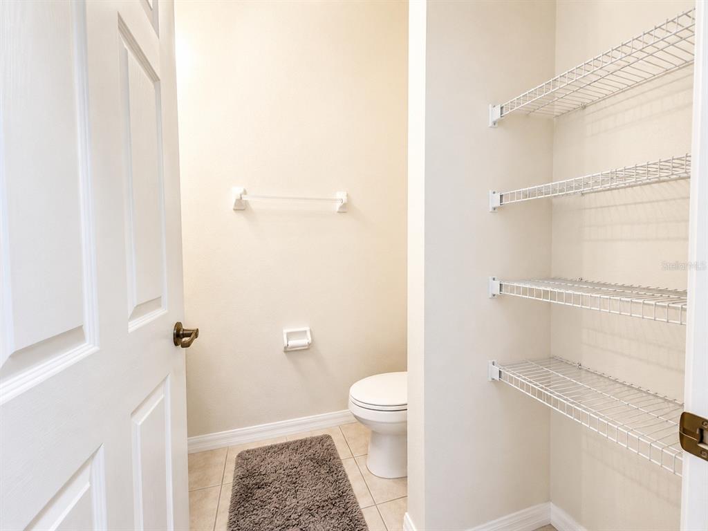 A small bathroom features a toilet, a towel bar, and open wire shelving — 4558 ADA LANE, KISSIMMEE, FL