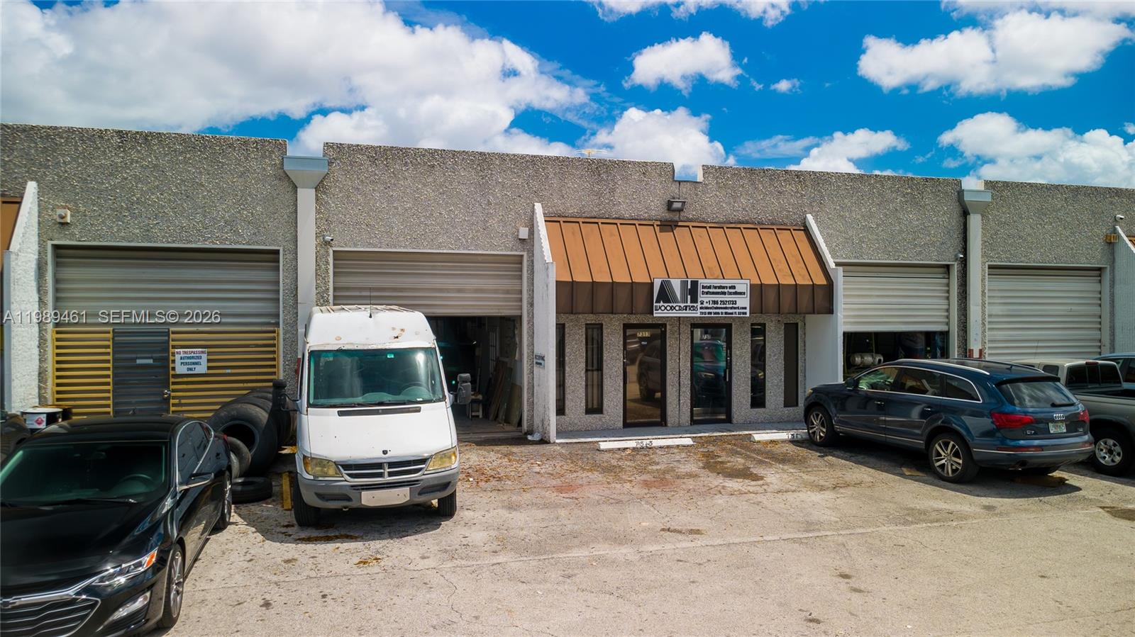 An exterior view of a commercial warehouse building with a metal awning and parking lot — 7313 NW 56th St # 7313, Miami FL 33166, MIAMI, FL