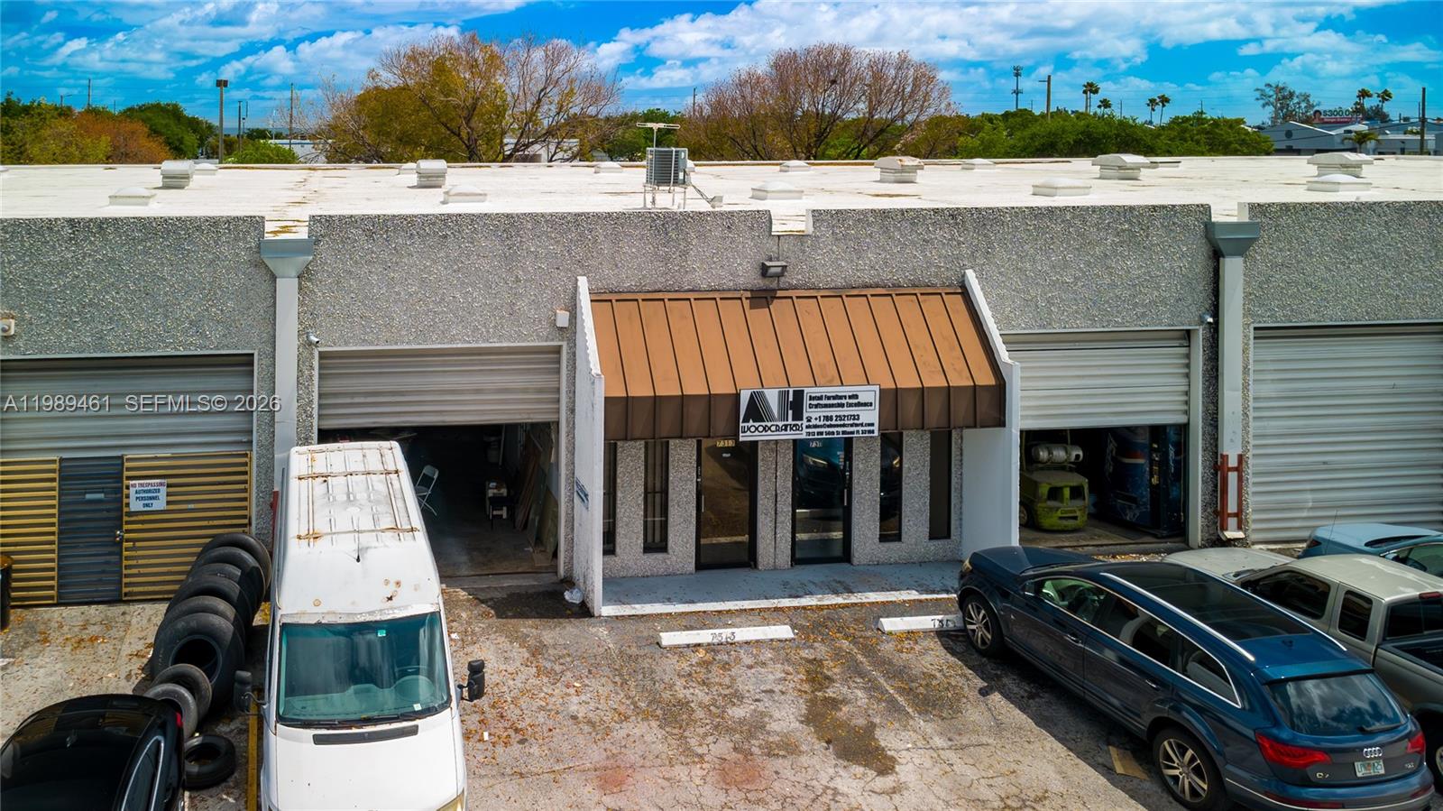 An exterior view of a commercial building with a central storefront and two garage bays — 7313 NW 56th St # 7313, Miami FL 33166, MIAMI, FL