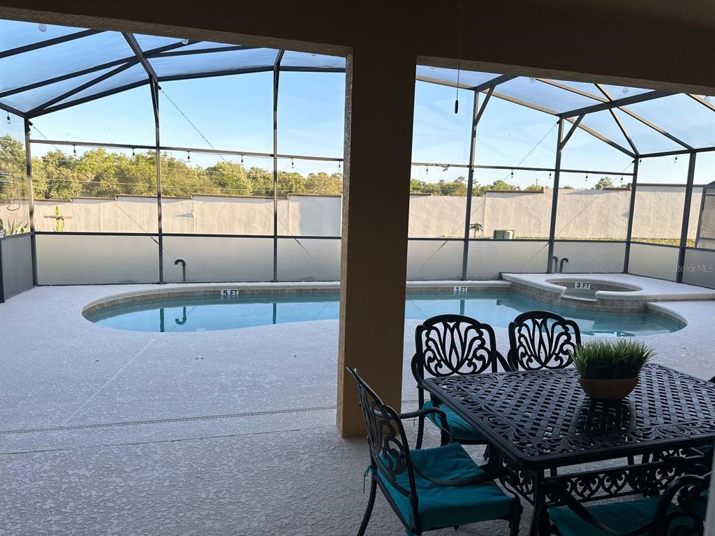 A screened-in patio features a swimming pool with a spa and outdoor dining furniture — 232 RUBINO DRIVE, DAVENPORT, FL