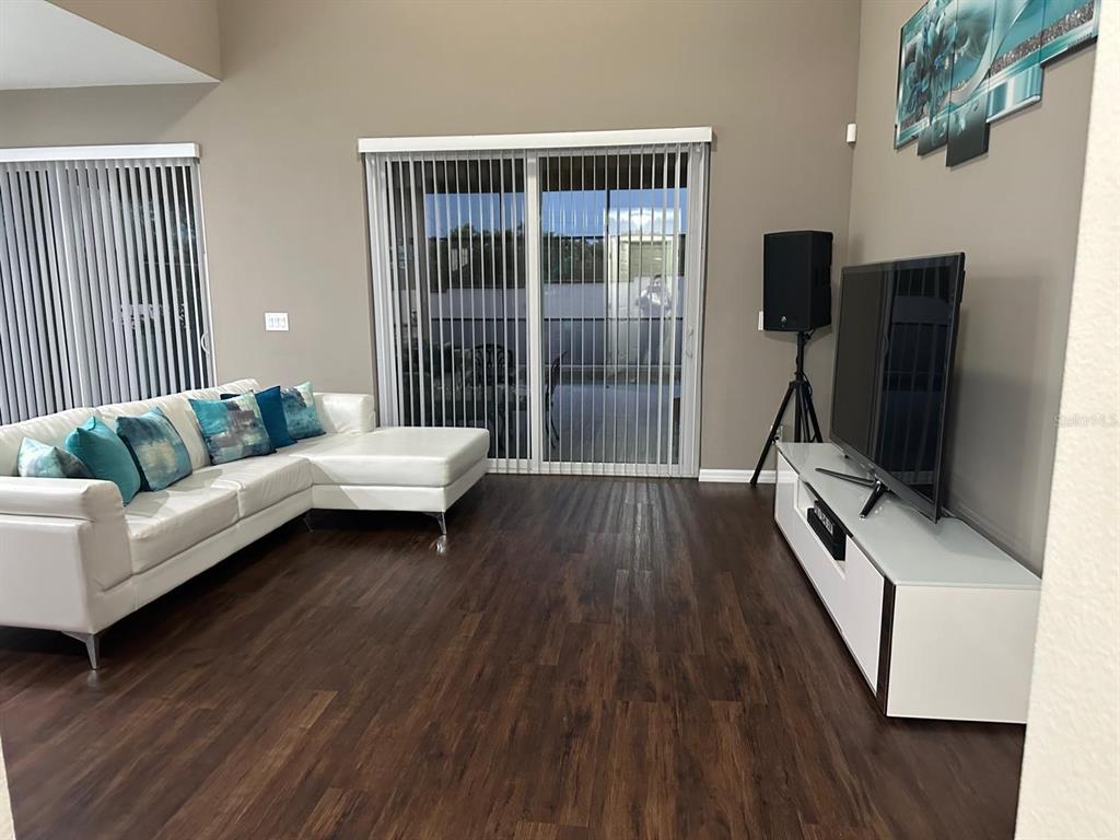 A living room features a white sectional sofa, dark wood flooring, and a television console — 232 RUBINO DRIVE, DAVENPORT, FL
