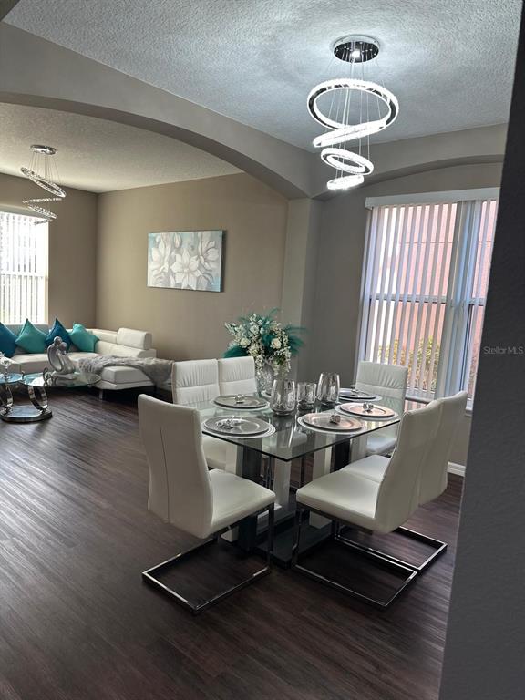 A dining area with a glass table and modern light fixture sits beside a living room — 232 RUBINO DRIVE, DAVENPORT, FL