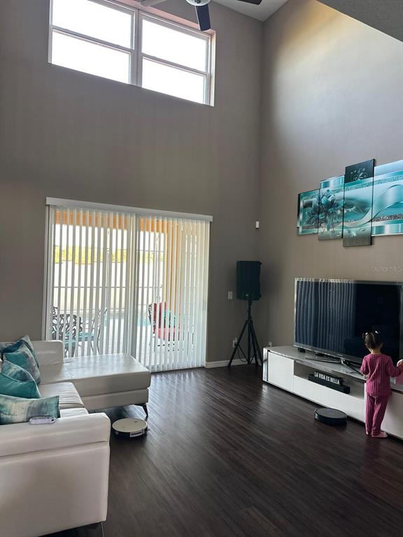 A living room features high ceilings, a white sectional sofa, a television, and sliding glass doors — 232 RUBINO DRIVE, DAVENPORT, FL