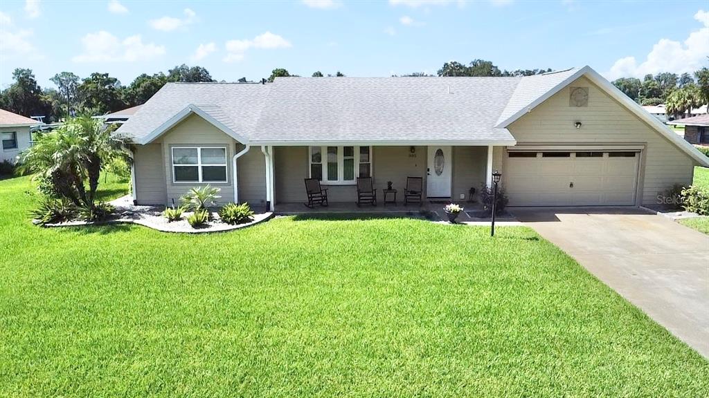 A single-story house with a beige exterior, a two-car garage, and a front lawn — 305 W DELAWARE STREET, TAVARES, FL