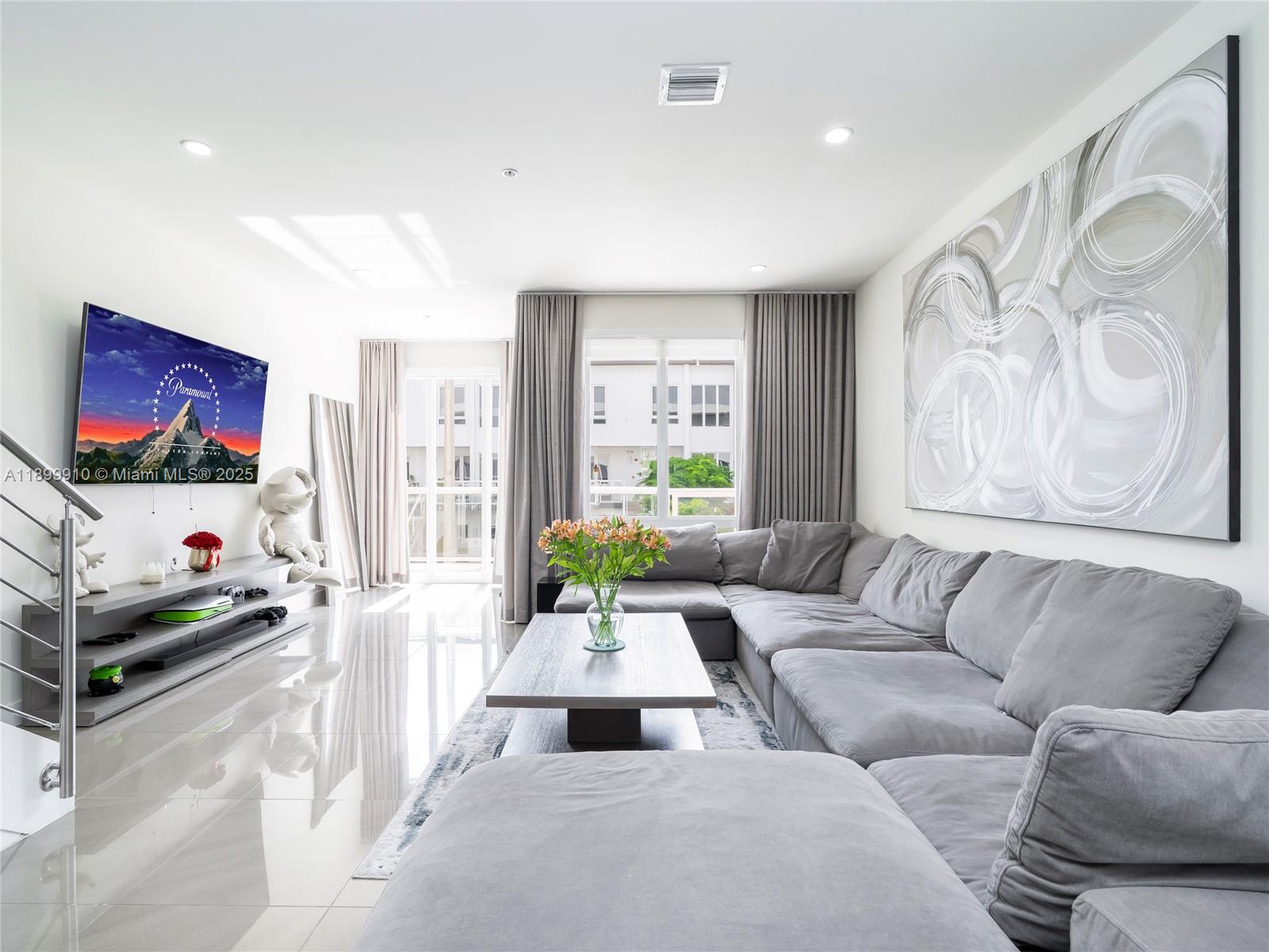 A modern living room features a large grey sectional sofa, a coffee table, and a television — 10245 NW 63rd Ter # 206, Doral FL 33178, DORAL, FL