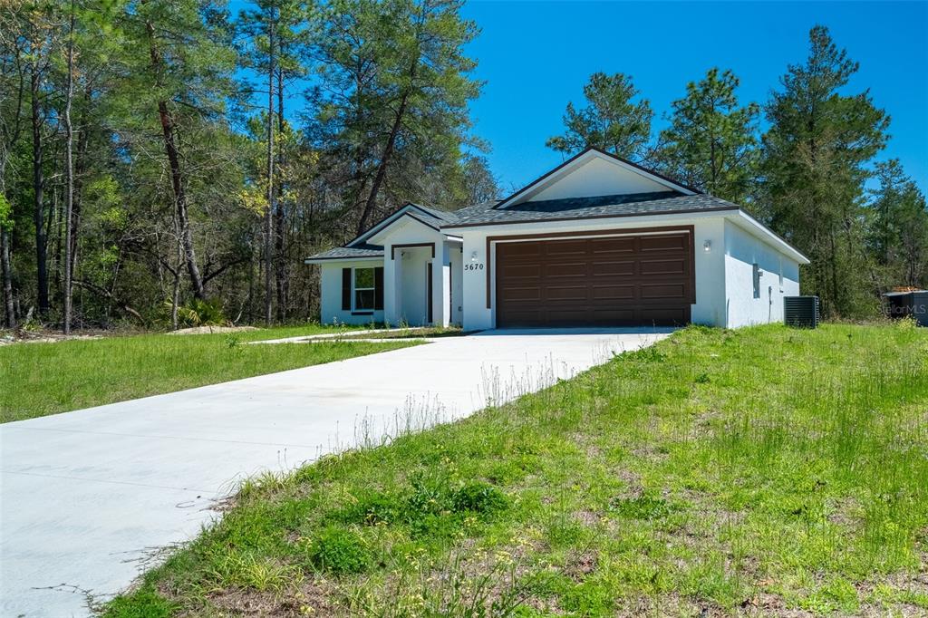 A single-story house with a white exterior, brown garage door, and a concrete driveway — 5670 SW 161ST PLACE, OCALA, FL