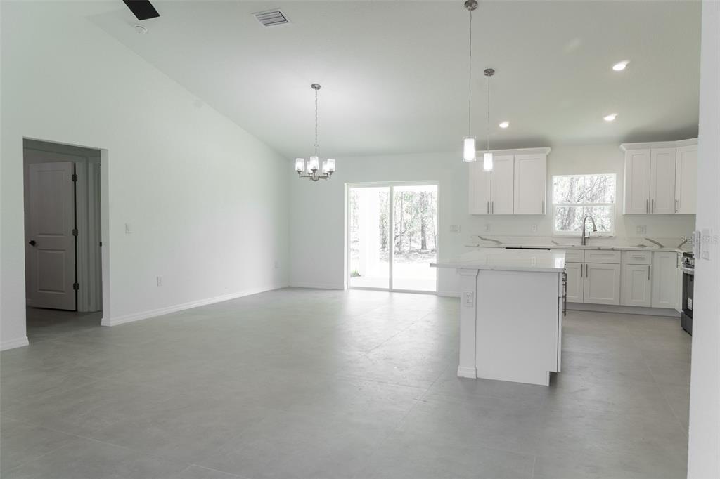 An open-concept kitchen and living area with white cabinets, a kitchen island, and tile flooring — 5670 SW 161ST PLACE, OCALA, FL