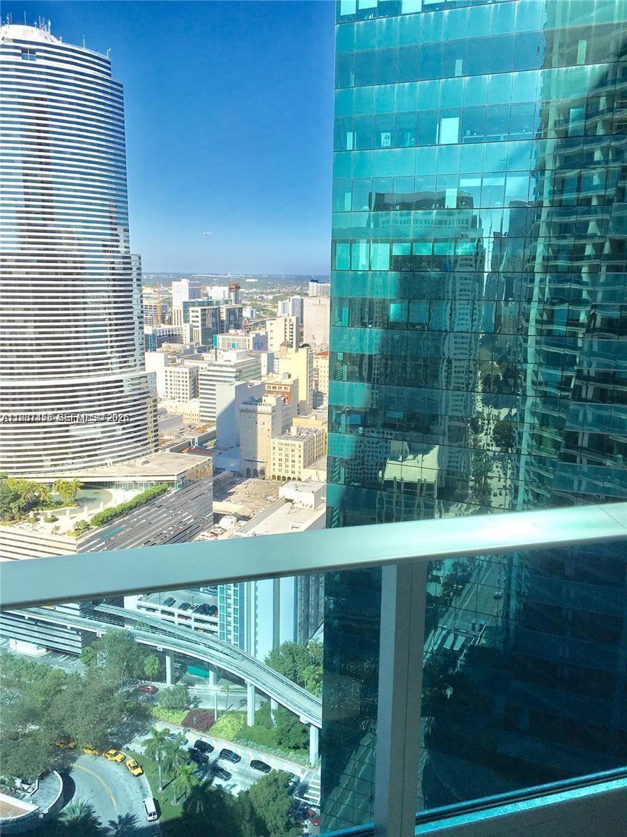 A high-rise balcony view overlooks a dense city skyline with modern glass skyscrapers — 200 Biscayne Boulevard Way # 3712, Miami FL 33131, MIAMI, FL