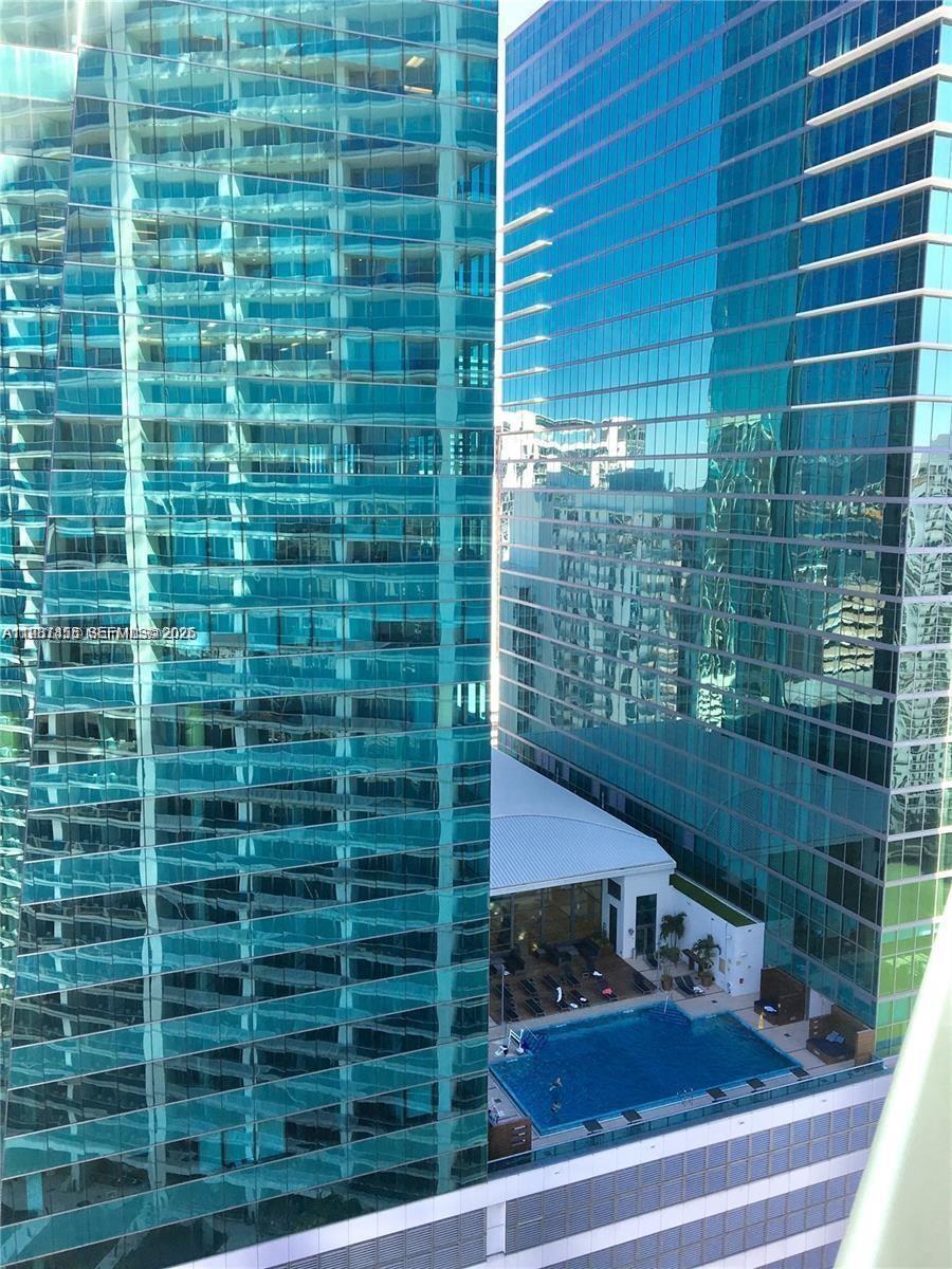 An elevated view shows a swimming pool nestled between two tall, blue glass-clad skyscrapers — 200 Biscayne Boulevard Way # 3712, Miami FL 33131, MIAMI, FL