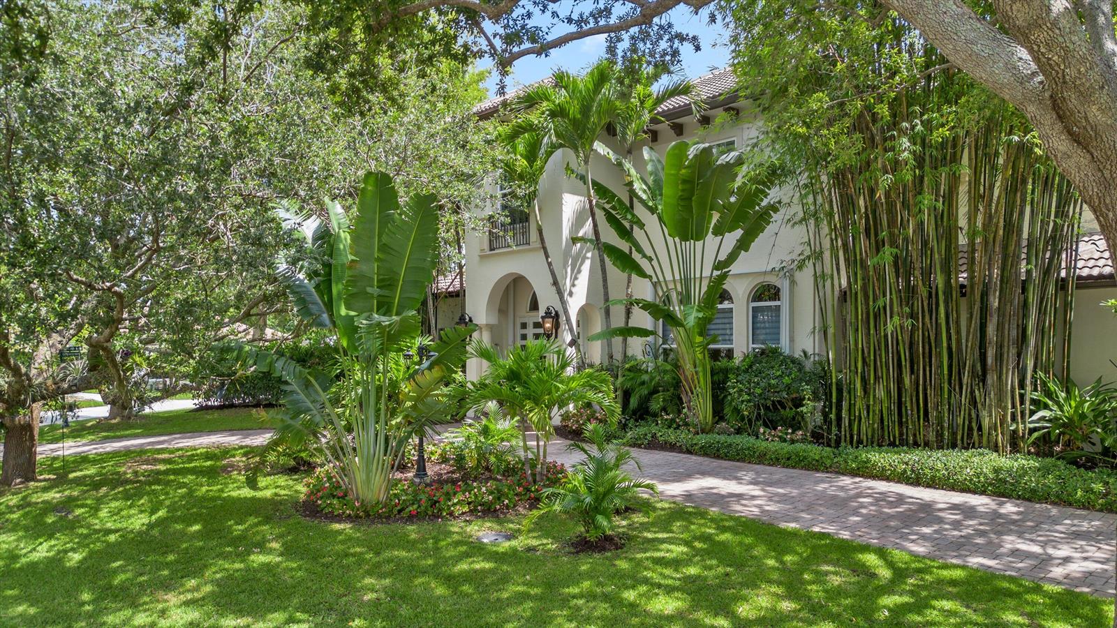 A two-story stucco house with a brick driveway, lush tropical landscaping, and tall bamboo stalks — 4699 Gleneagles Drive, Boynton Beach FL 33436, BOYNTON BEACH, FL