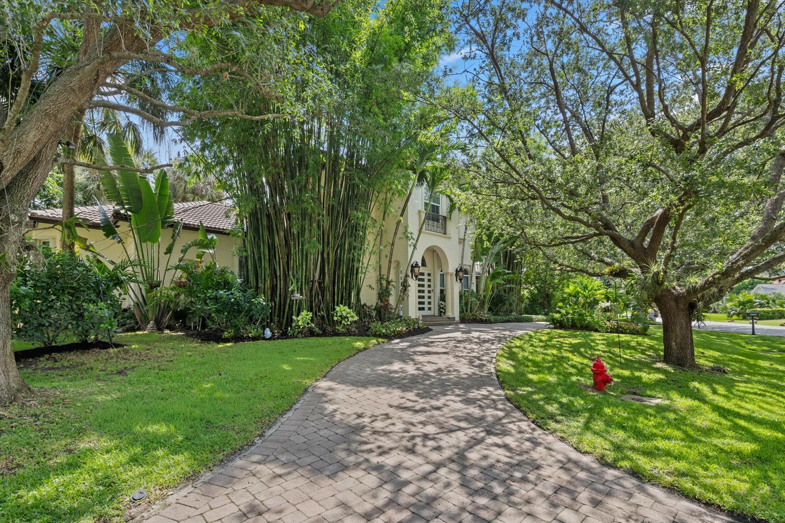 A paved driveway leads to the entrance of a two-story home surrounded by lush landscaping — 4699 Gleneagles Drive, Boynton Beach FL 33436, BOYNTON BEACH, FL