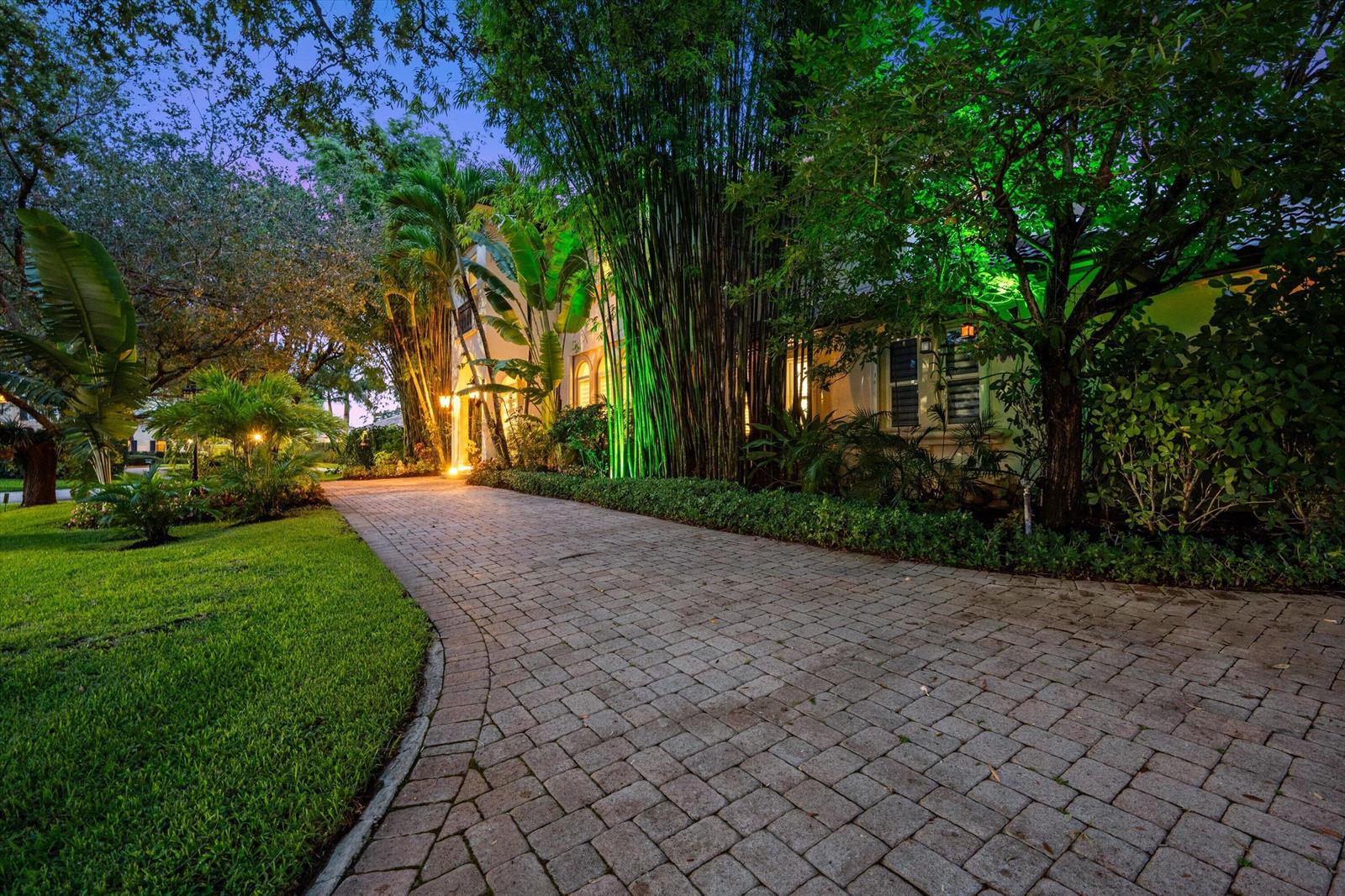 A paved driveway leads to a house surrounded by lush tropical landscaping and tall bamboo — 4699 Gleneagles Drive, Boynton Beach FL 33436, BOYNTON BEACH, FL