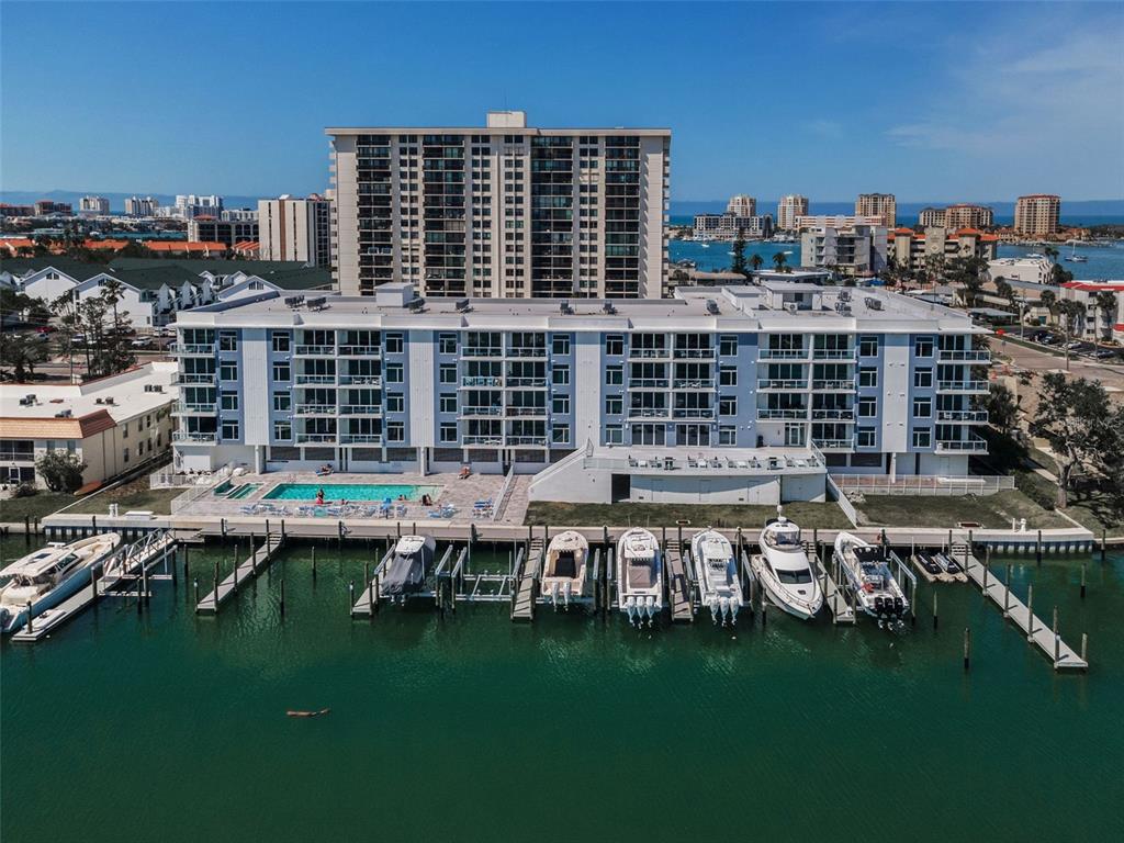 An aerial view of a multi-story apartment building with a swimming pool and boat docks — 415 ISLAND WAY UNIT 509, CLEARWATER BEACH, FL