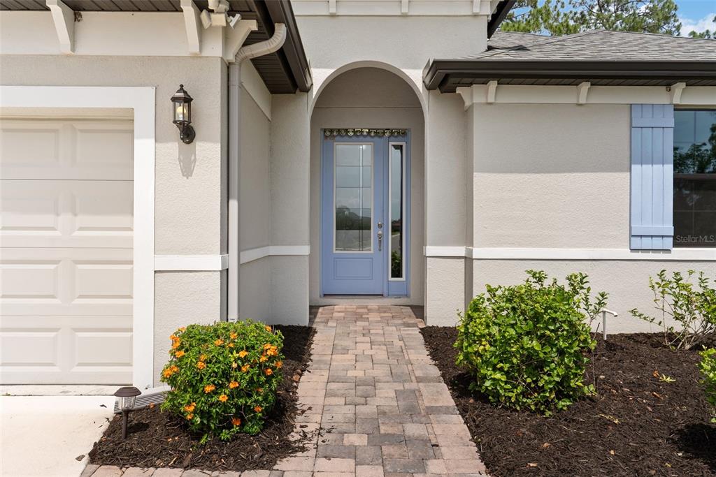 A light blue front door sits under an arched entryway with a stone paver walkway — 3918 GAVIOTA DRIVE, SUN CITY CENTER, FL
