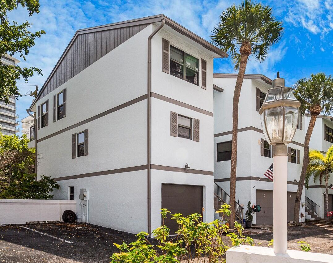 A three-story white townhouse with a garage and brown trim under a blue sky — 3250 NE 12th Street # 1, Pompano Beach FL 33062, POMPANO BEACH, FL