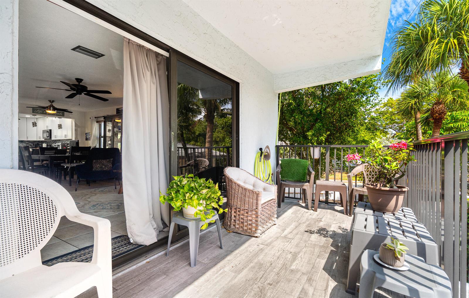 A balcony with wood-look tile flooring features outdoor seating, potted plants, and a sliding glass door — 3250 NE 12th Street # 1, Pompano Beach FL 33062, POMPANO BEACH, FL
