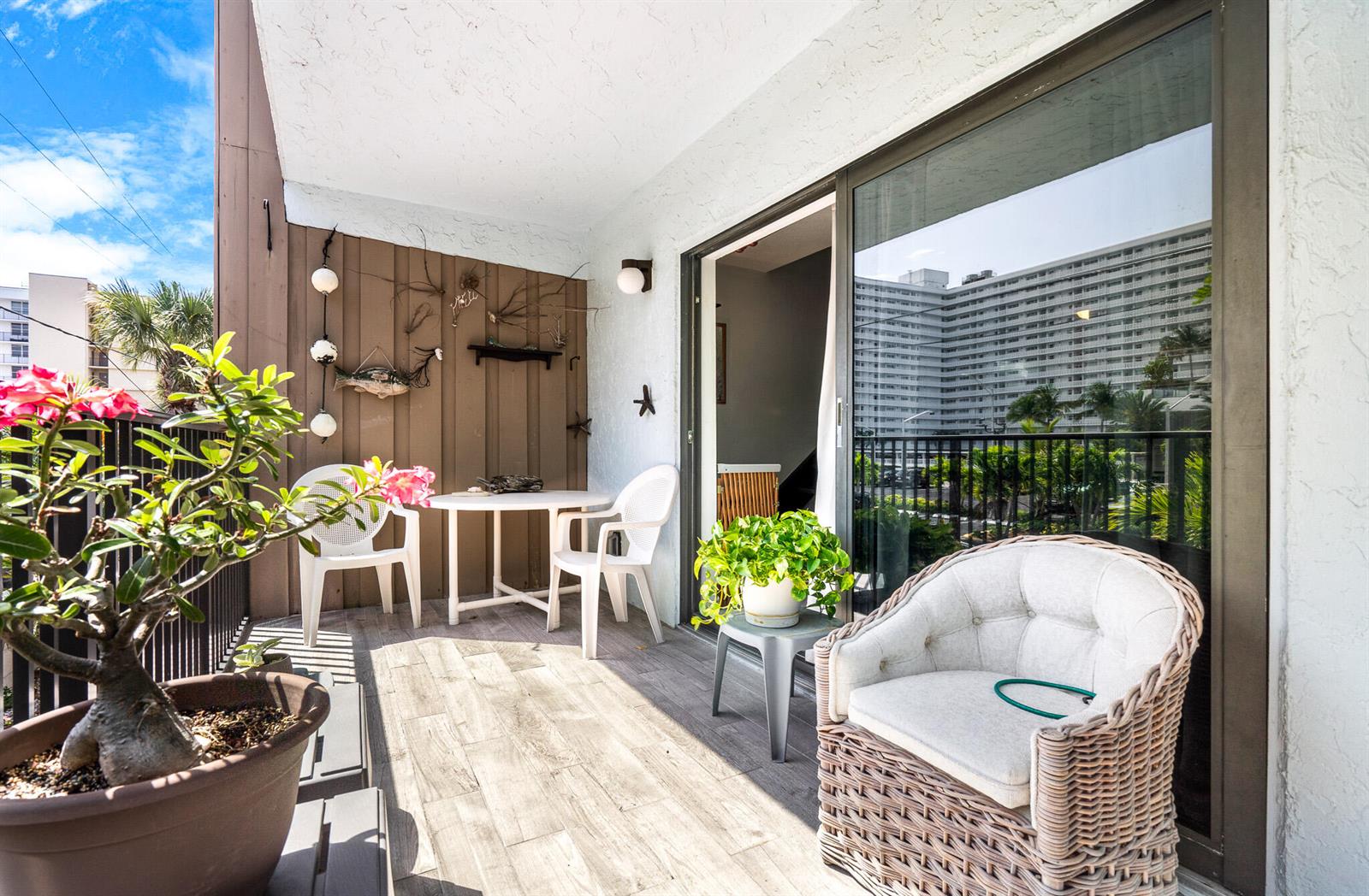 A balcony features a small dining set, a wicker chair, and a potted plant — 3250 NE 12th Street # 1, Pompano Beach FL 33062, POMPANO BEACH, FL