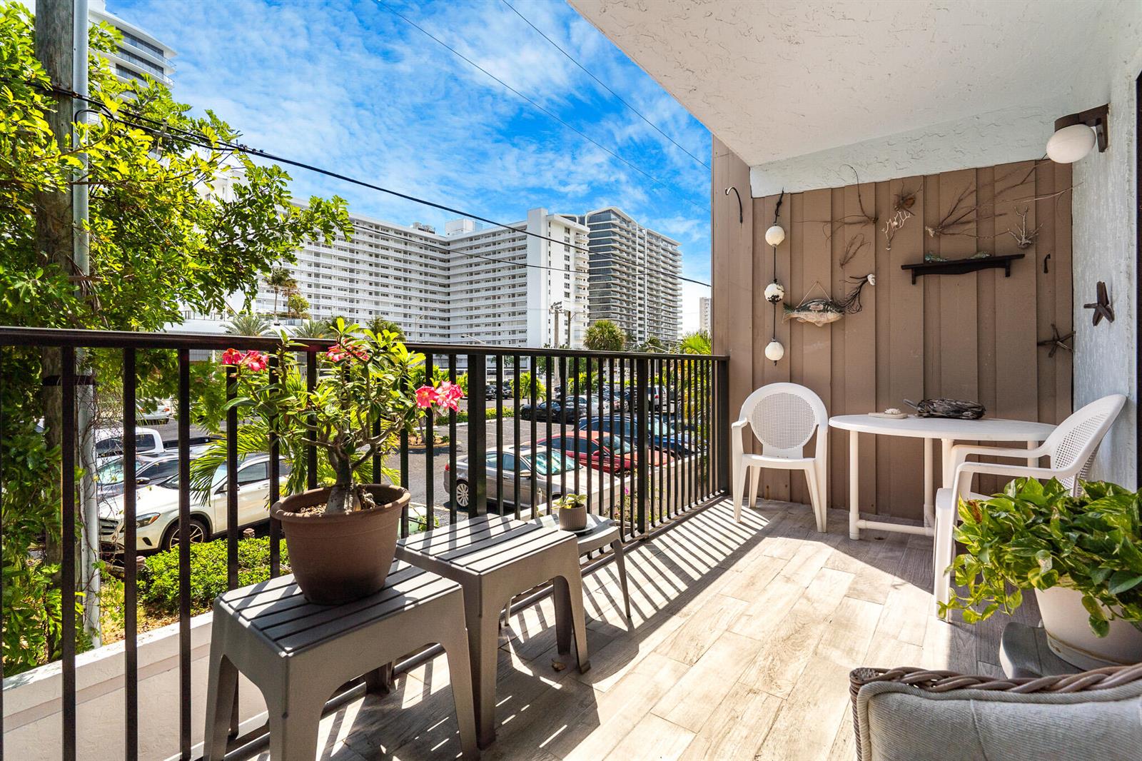 A balcony with a table, chairs, potted plants, and a view of a large apartment building — 3250 NE 12th Street # 1, Pompano Beach FL 33062, POMPANO BEACH, FL
