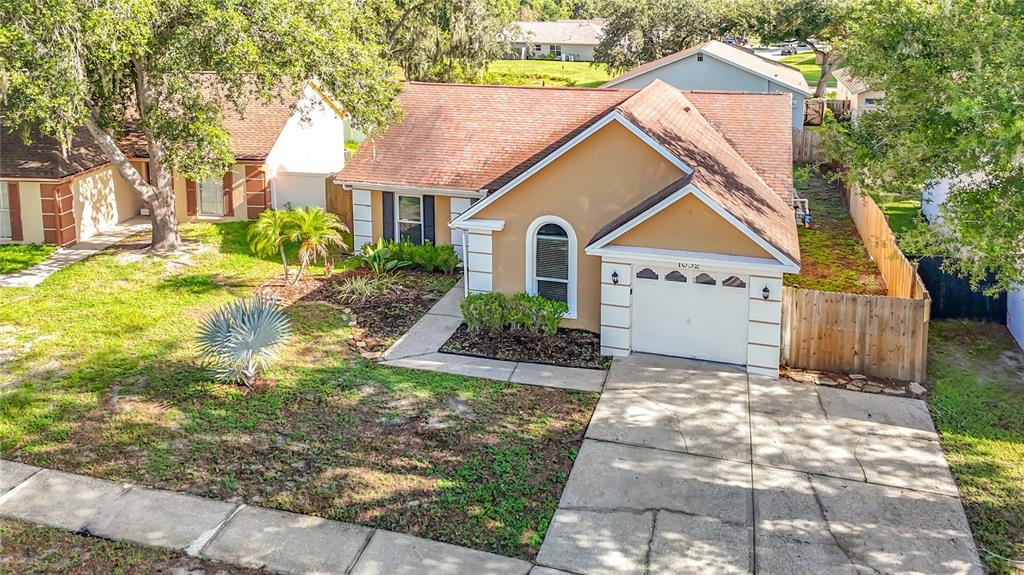 An elevated view of a tan single-story house with a white garage and driveway — 1032 HARDWOOD DRIVE, VALRICO, FL